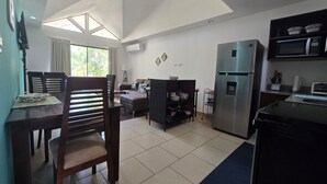 A modern kitchen with a refrigerator, microwave, and dining area with chairs and a table. - Casa Azules Jungle Villa 3 piscinas near the beach (Venado)