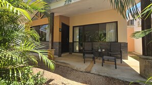 A modern building with a large glass door, a patio with two chairs, and a palm tree in the foreground. - Casa Azules Jungle Villa 3 piscinas near the beach (Venado)