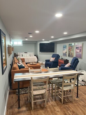 A living room with a sectional sofa, a dining table with chairs, a TV mounted on the wall, and framed pictures. - Cozy charmer walking distance to ND! Plenty of driveway and street parking. (South Bend)