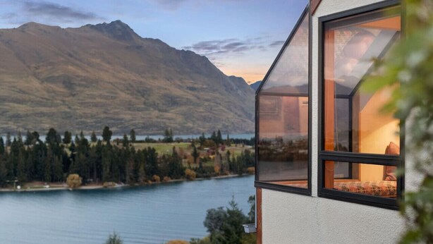 A modern house with a large window overlooking a lake and mountains. - Swallowdale | A home away from home, close to town (Queenstown)