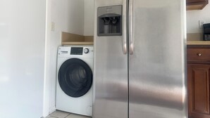Eine kompakte Küche mit Edelstahlkühlschrank, integriertem Waschmaschine und Holzschränken.