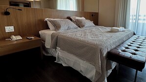 Una habitación de hotel moderna con una cama grande, mesitas de noche, un teléfono y un espejo.