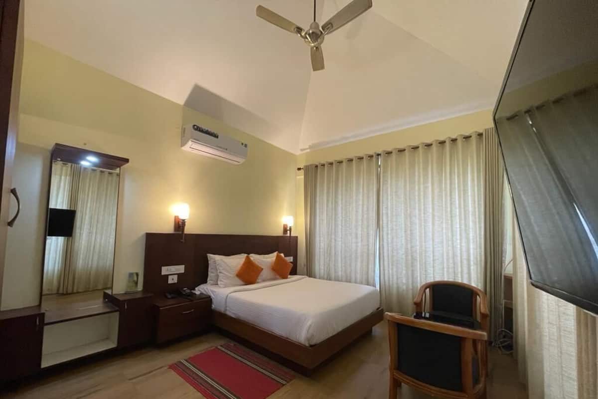 A hotel room with a bed, bedside table, chair, and a ceiling fan.