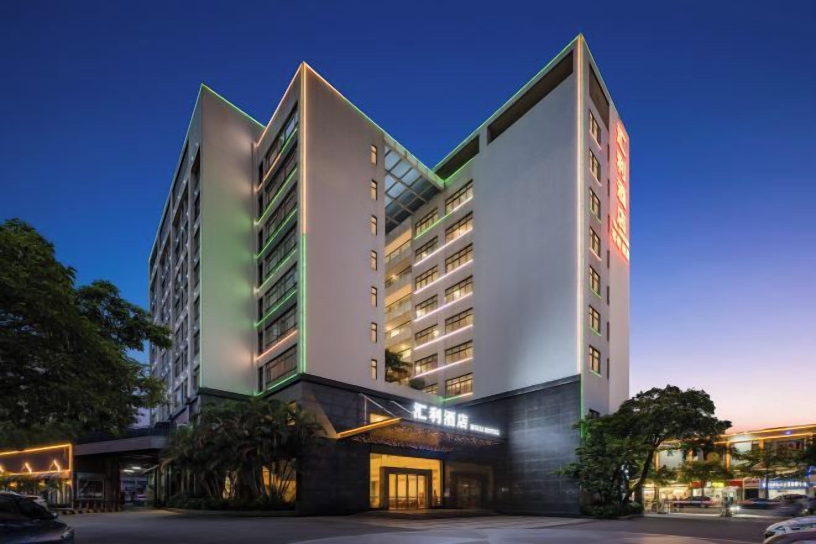 A modern hotel with multiple floors, a prominent entrance, and illuminated signage.