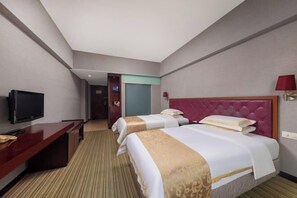 Ein Hotelzimmer mit zwei Betten, einem Fernseher, einem Schreibtisch und einer roten Lampe.