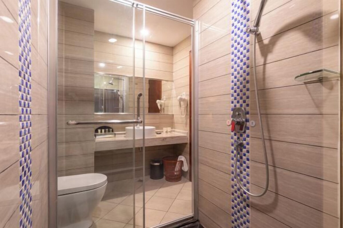 A modern bathroom with a glass-enclosed shower, a toilet, and a sink.