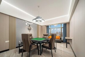 A modern room with a pool table, comfortable seating, and a large window offering a city view.