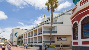 A building with multiple balconies, a palm tree, and a sign for a sports club.