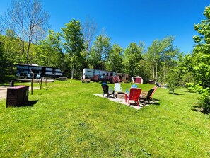 En campingplads med autocampere, picnicborde og udendørs siddepladser.