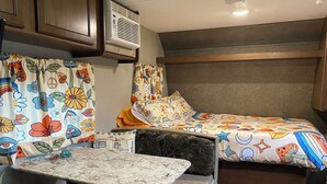 A compact RV interior with a bed, a small kitchenette, and a dining area. - HideOut in The Highlands 
15min from Skyline Trail
Walking distance from Sunsets (Pleasant Bay)
