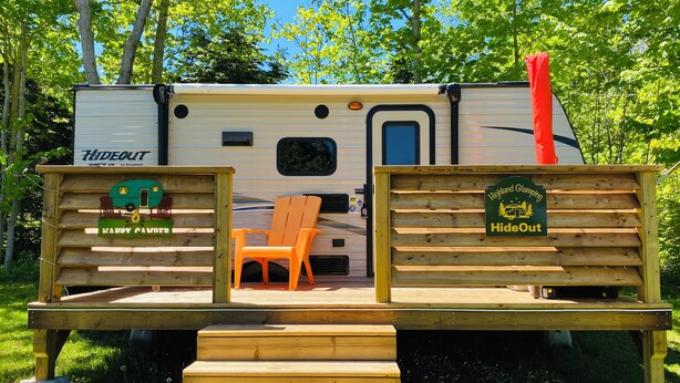 A camper with a deck, a chair, and a sign that reads "Highland Glamping HideOut." - HideOut in The Highlands 
15min from Skyline Trail
Walking distance from Sunsets (Pleasant Bay)