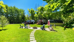 A campsite with a Starcraft RV, a small shed, and a fire pit area with chairs. - HideOut in The Highlands 
15min from Skyline Trail
Walking distance from Sunsets (Pleasant Bay)