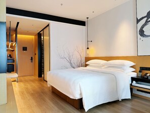 A modern hotel room with a large bed, a wooden floor, a wardrobe, and a desk with a chair. - Fairfield By Marriott Shenzhen Bao'an (Shenzhen)