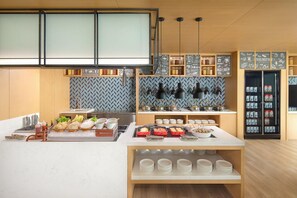 Une cuisine moderne dotée d’un îlot central, de divers produits alimentaires et d’un tableau noir servant de menu.