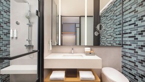 Een moderne badkamer met een glazen douchecabine, een witte wastafel en een toilet.