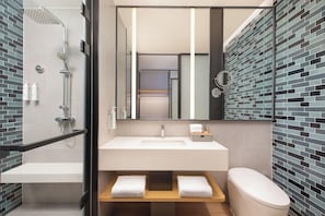 Ein modernes Badezimmer mit einer Duschkabine aus Glas, einem weißen Waschbecken und einer Toilette.