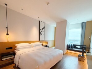A modern hotel room with a large bed, a city view, a sofa, and a minimalist design. - Fairfield By Marriott Shenzhen Bao'an (Shenzhen)