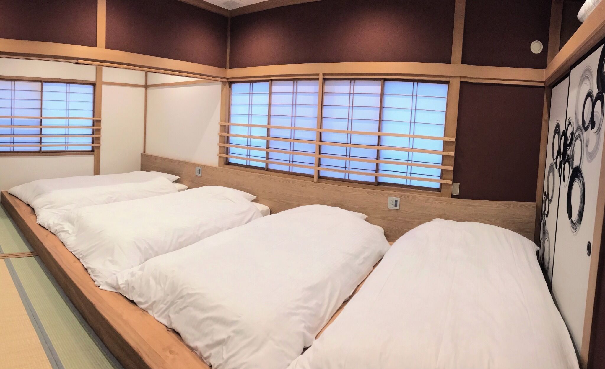 A traditional Japanese-style room with tatami flooring, shoji screens, and a tatami mat bed.
