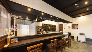 Zona de bar con mostrador, taburetes y un elemento decorativo en la pared.
