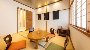 Una habitación tradicional japonesa con suelo de tatami, una mesa redonda de madera y bajos armarios de madera.