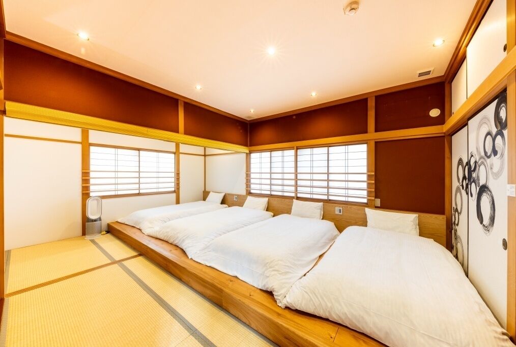 A traditional Japanese-style room with tatami flooring, a low wooden platform bed, and sliding doors.