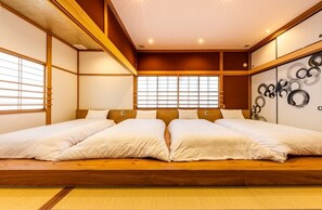 Una habitación tradicional japonesa con suelo de tatami, una cama de madera baja con ropa de cama blanca y un fusuma con un diseño circular.