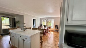 Una cocina amplia con piso de madera, armarios blancos y un comedor con mesa y sillas.
