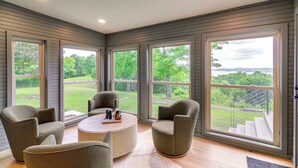 Una habitación amplia con ventanas grandes, una mesa de centro redonda y asientos cómodos.