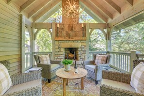A covered porch with wicker furniture, a stone fireplace, and a chandelier. - Designer Cashiers Cottage, Perfect Porch, EV Plug (Cashiers)