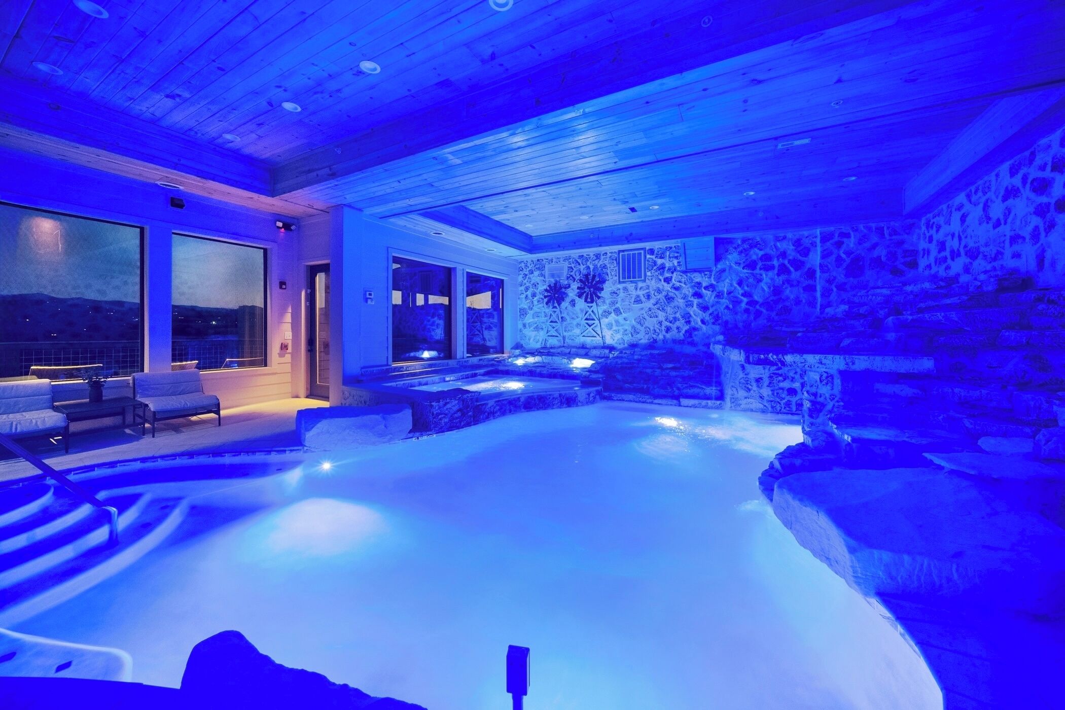 A spa area with a hot tub, seating, and a stone wall.