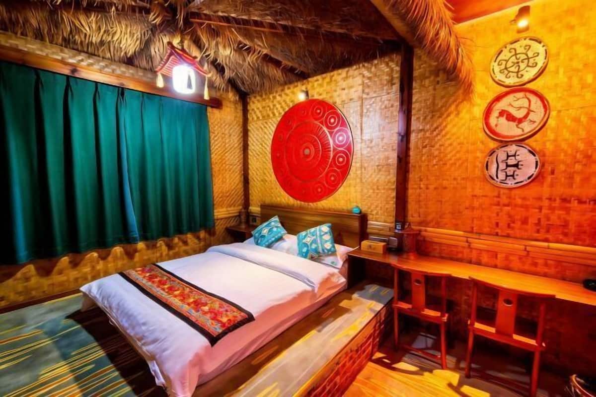 A room with a bed, a wooden bench, and a wall with decorative plates.