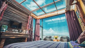 Ein Zimmer mit einem großen Oberlicht, einem Bett, einem Fernseher und Blick auf den Himmel.