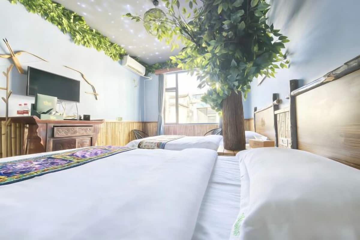 A hotel room with two beds, a television, a desk, and a large window.