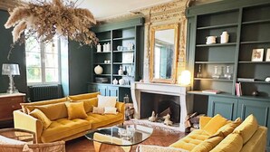 A living room with a yellow sofa, a glass coffee table, and a fireplace. - Maison de Charme Pour Événements Familiaux ou Professionnels Domaine Le Pinquat (La Lande-de-Fronsac)