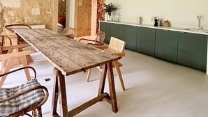 A rustic dining area with a wooden table and chairs, a kitchen with wooden cabinets, and hanging paper lanterns. - Maison de Charme Pour Événements Familiaux ou Professionnels Domaine Le Pinquat (La Lande-de-Fronsac)