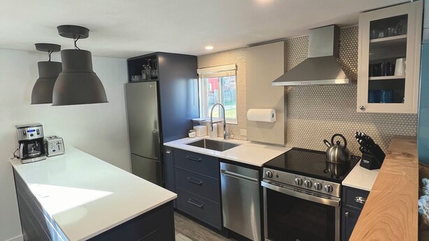 A modern kitchen with a central island, stainless steel appliances, and a wooden countertop. - Little Blue on Second St! Cozy & close to the beach, pub, bar, and downtown! (Port Stanley)