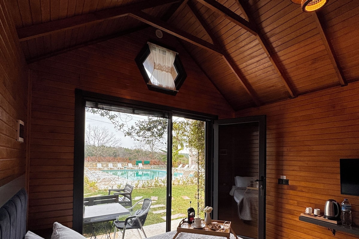Une chambre avec un grand lit, une vue sur la piscine et un plafond en bois.