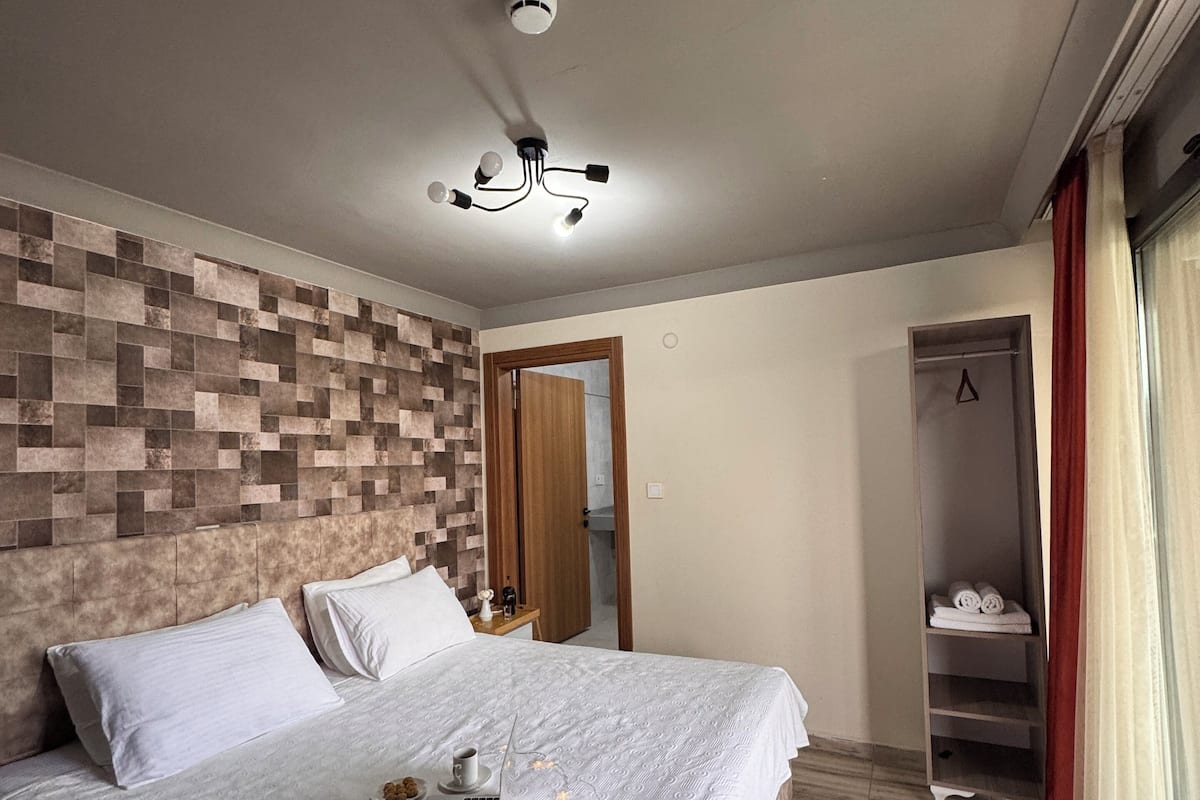 Une chambre à coucher avec un lit, un ordinateur portable et un luminaire au plafond.