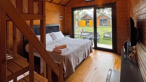 Een gezellig houten slaapkamer met een stapelbed, een bureau en een groot raam met uitzicht op de omgeving.