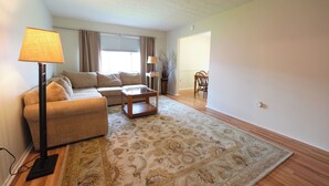 A living room with a sofa, a coffee table, a lamp, and a patterned rug. - Spacious Home Near WEC, The Roberts Center and Wilmington College (Wilmington)