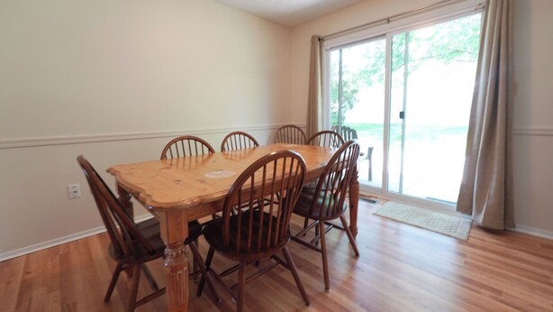 A dining room with a wooden table and chairs, a sliding glass door, and a light-colored floor. - Spacious Home Near WEC, The Roberts Center and Wilmington College (Wilmington)