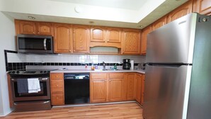 A kitchen with wooden cabinets, stainless steel appliances, and a patterned rug. - Spacious Home Near WEC, The Roberts Center and Wilmington College (Wilmington)
