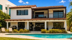 A two-story house with a swimming pool, outdoor seating, and a balcony.