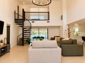 A spacious living area with a modern staircase, a dining area with a view, and a kitchen with white cabinets. - Española Bayfront Villa – North Bay Village Luxury (North Bay Village)
