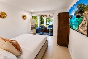 A bedroom with a bed, a wardrobe, a large window, and a view of an outdoor seating area. - Española Bayfront Villa – North Bay Village Luxury (North Bay Village)