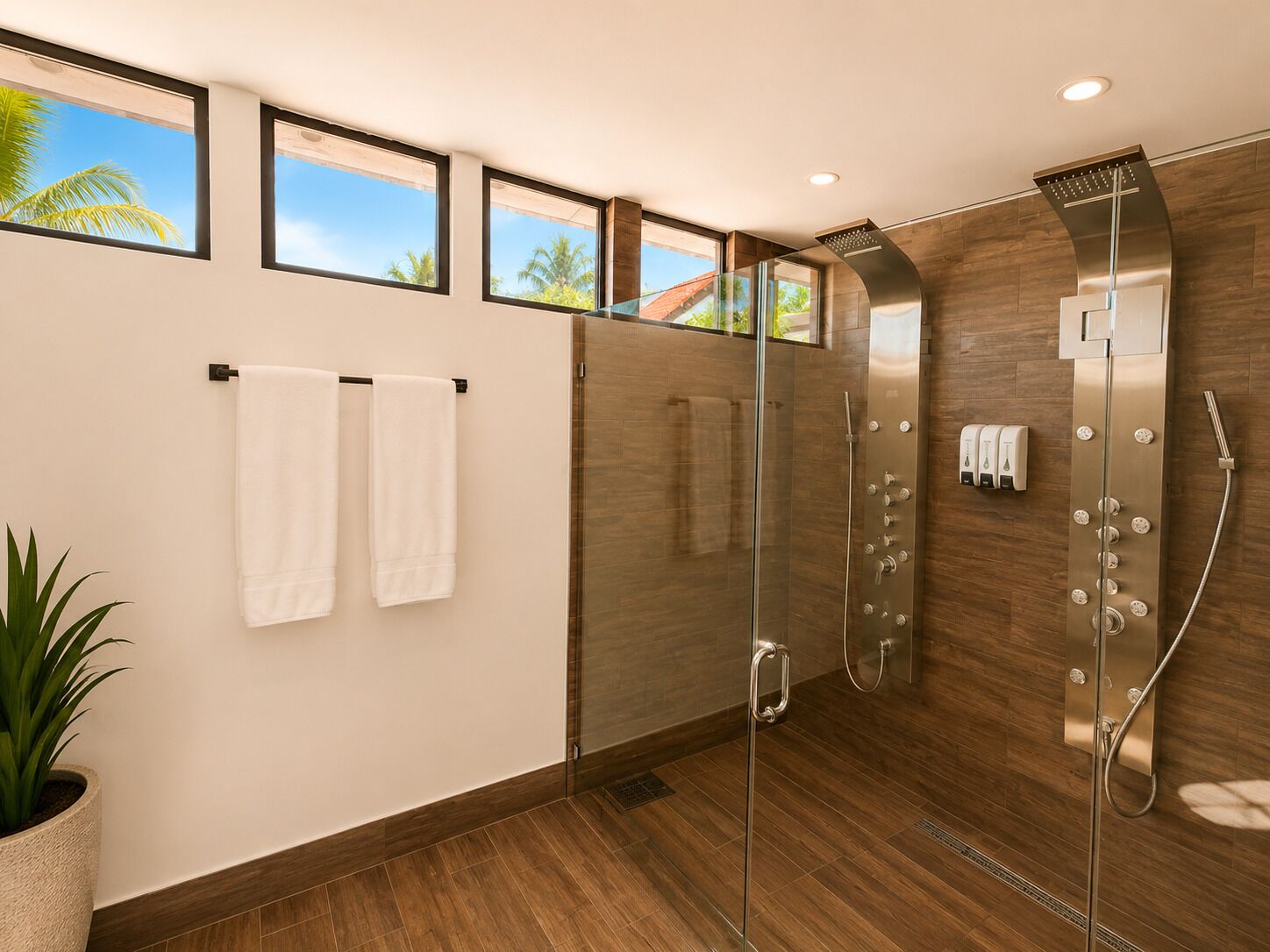 Ein modernes Badezimmer mit einer in Glas abgeschirmten Dusche, Holzboden und einem Blumentopf.