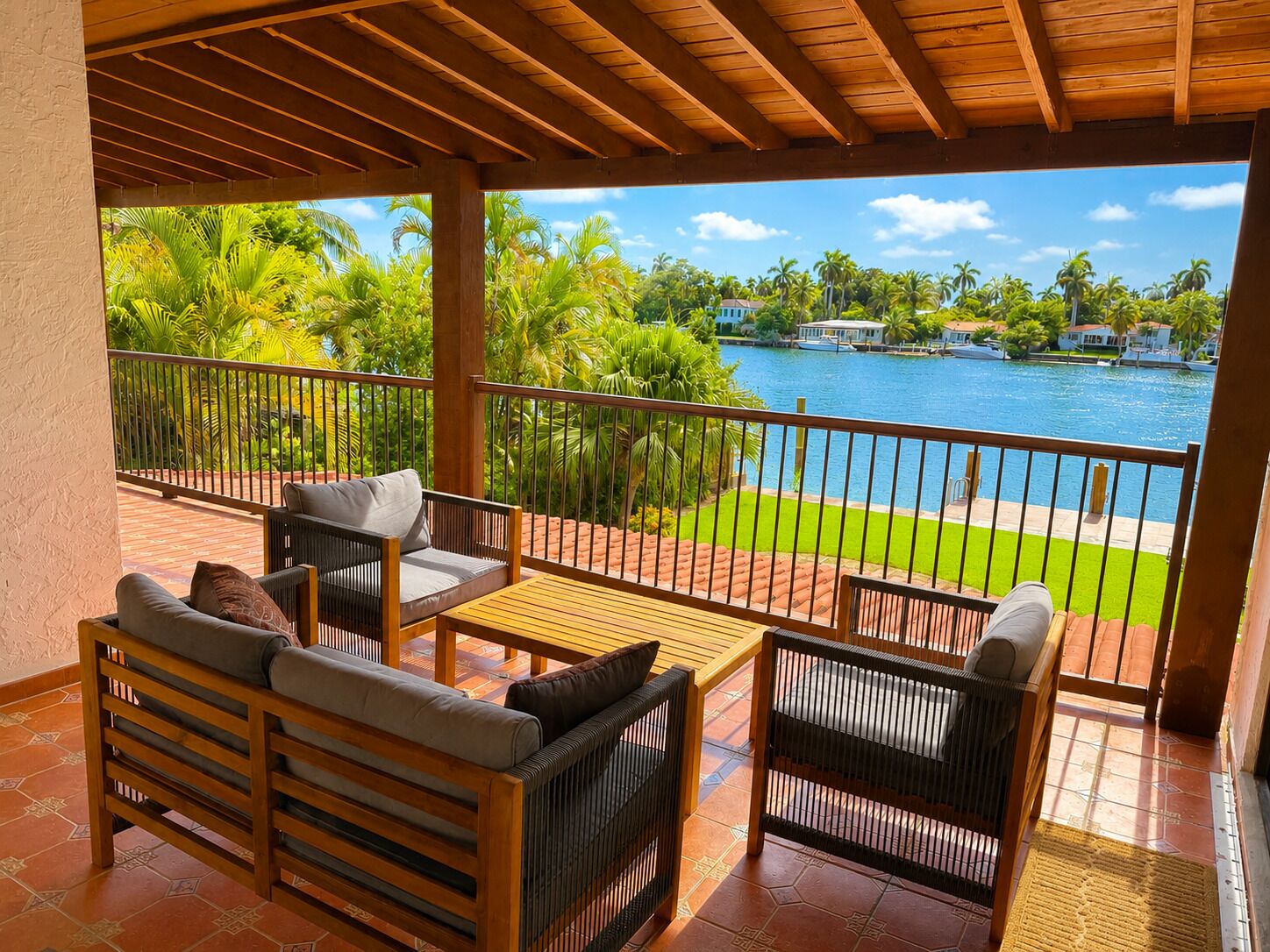 A covered outdoor seating area with a view of a lake and palm trees.