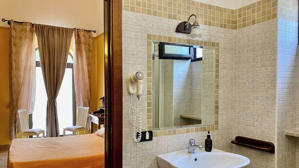 A hotel room with a bed, a bathroom with a sink, a mirror, and a hairdryer. - Double room with single beds - Zudinì (Sternatia)