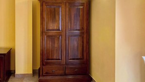 A wooden wardrobe with two doors and two drawers, located in a hallway with yellow walls and a light fixture above. - Double room with single beds - Zudinì (Sternatia)