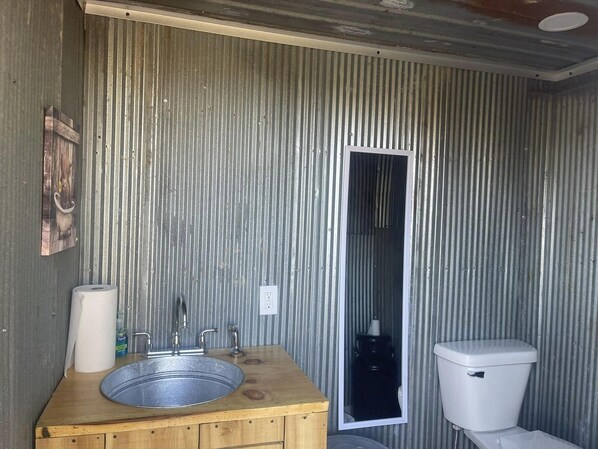 Een badkamer met een houten wastafelmeubel, een wastafel, een toilet en een spiegel.